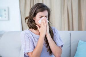 Air duct cleaning for allergies Lynchburg — woman sneezing on sofa